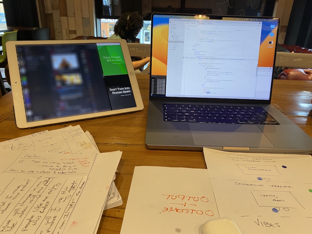 Working at a table at a coffee shop with a laptop and ipad